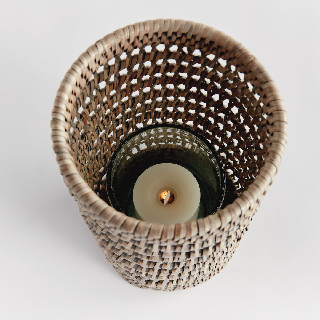 Top view into a small graywash rattan hurricane showing a candle within its glass insert and open woven sides, Transitional
