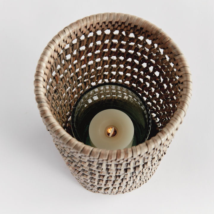 Top view into a small graywash rattan hurricane showing a candle within its glass insert and open woven sides, Transitional