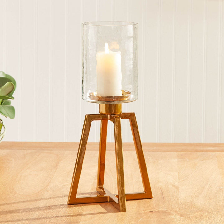 Gold metal hurricane candle holder with hammered glass, styled on wood console with soft natural light – Industrial Modern


