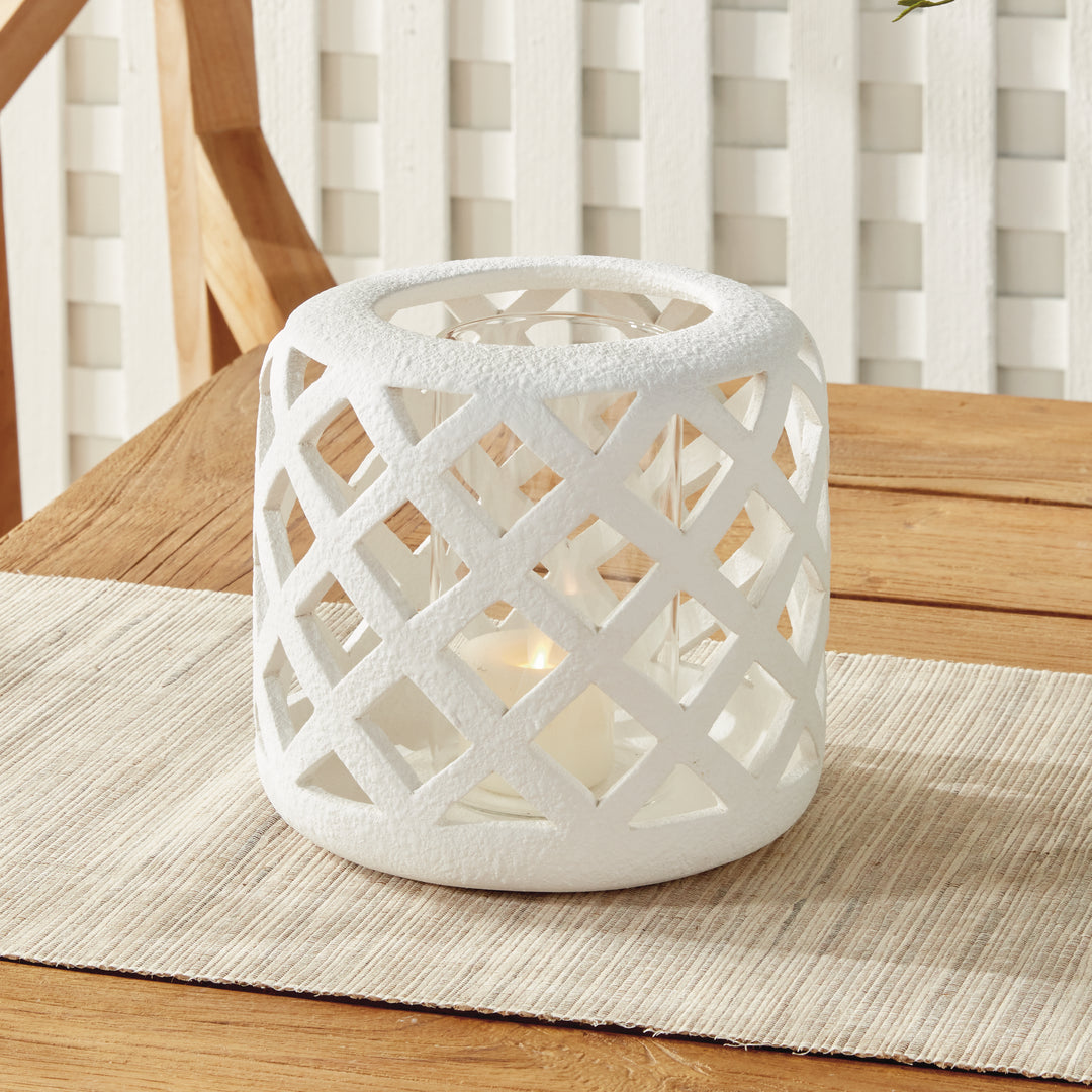 Small white terracotta hurricane candle holder styled on tabletop with warm candlelight – Modern Organic style.