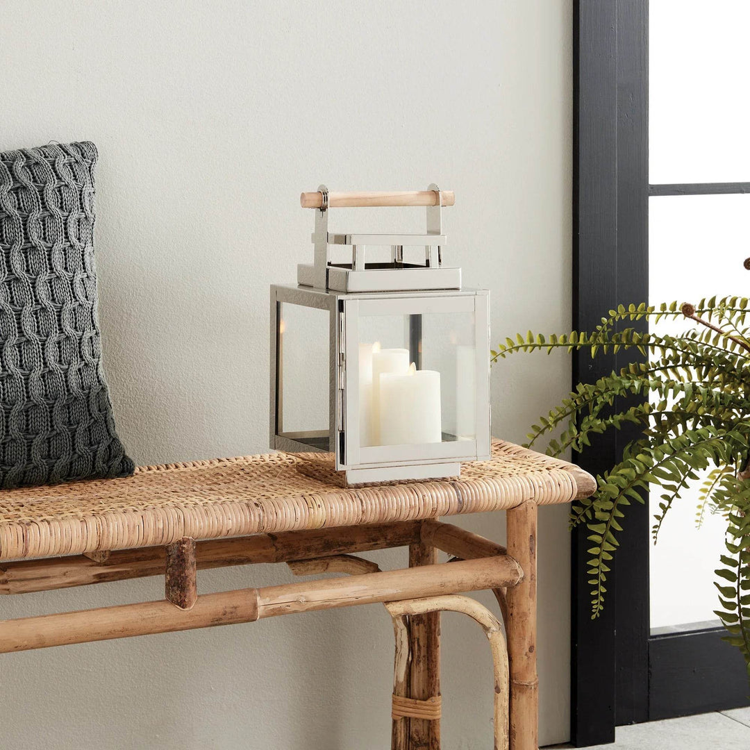 Small silver lantern with teak handle styled on bench, glowing pillar candles inside