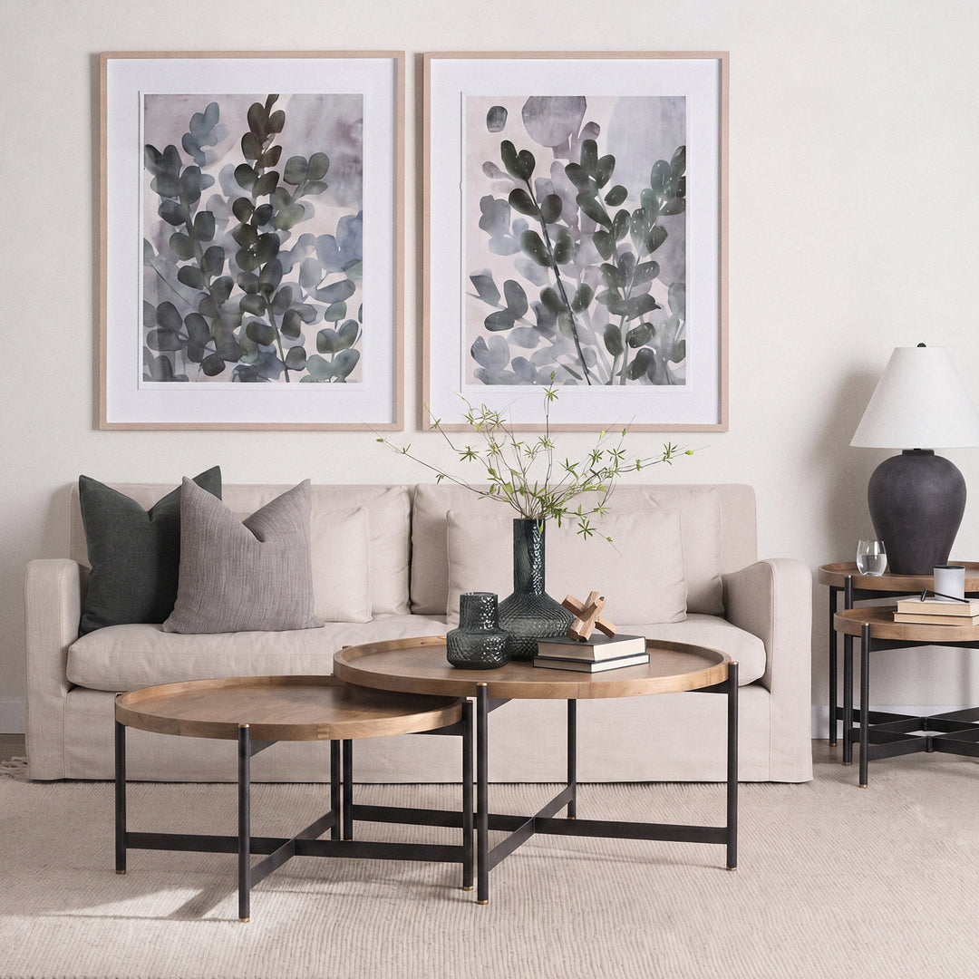 Round mango wood coffee table with black iron base styled in a warm neutral living room, Modern Organic coffee table