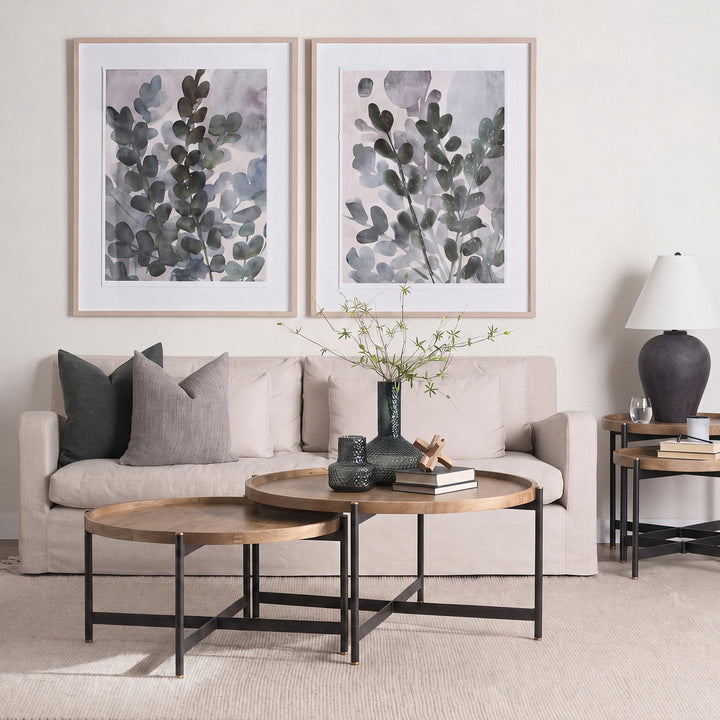 Round mango wood coffee table with black iron base styled in a warm neutral living room, Modern Organic coffee table