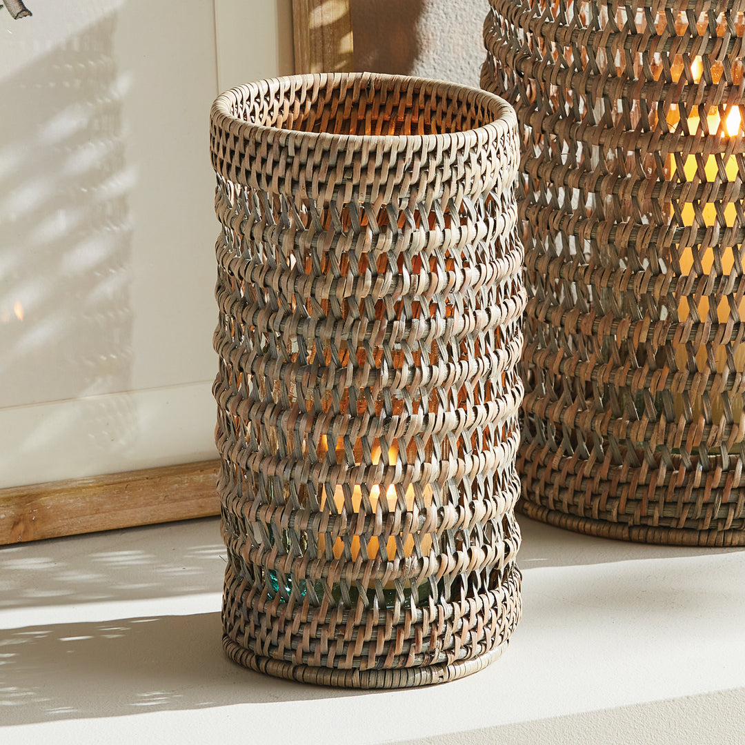 Small warm brown rattan hurricane with a candle inside, styled beside a larger matching hurricane on a console, Transitional