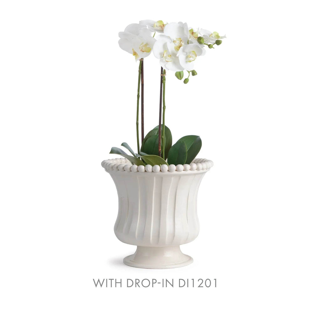 White ceramic vase with decorative beads holding white flowers on a white background