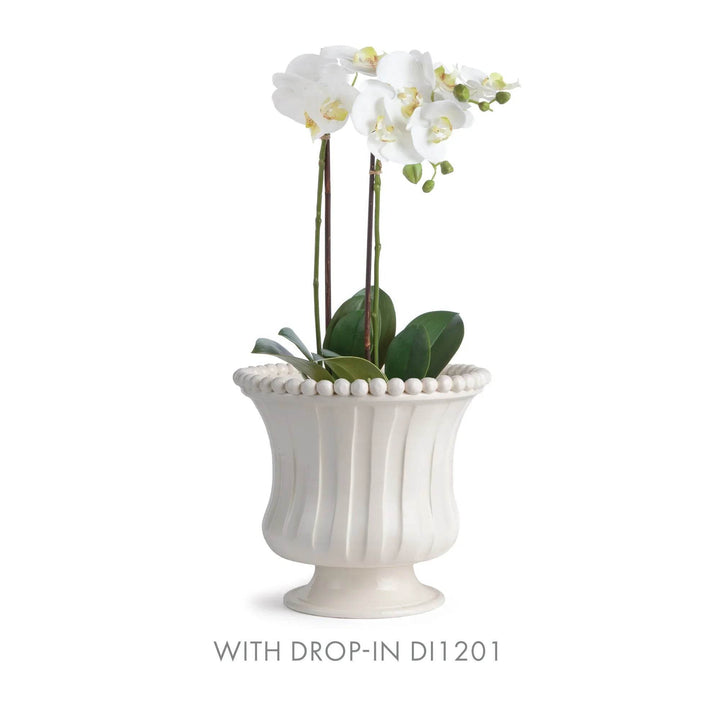 White ceramic vase with decorative beads holding white flowers on a white background