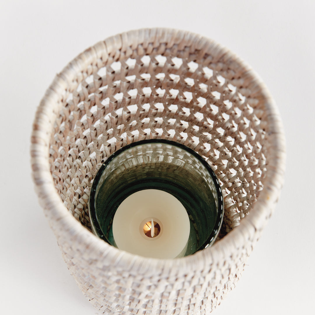 Top view into a small whitewash rattan hurricane showing a candle inside the glass insert and the woven sides, Transitional