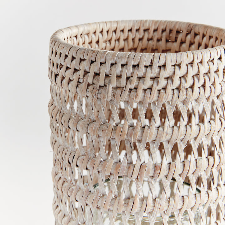 Close view of a small whitewash rattan hurricane showing the woven rim and open woven pattern against white, Transitional