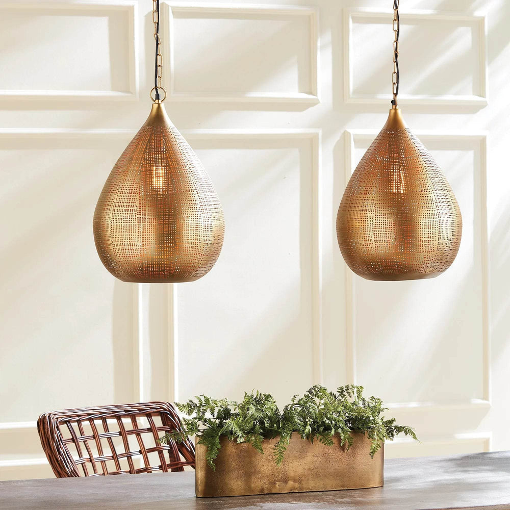 Pair of small gold woven iron pendants above a dining table with greenery, woven chairs and paneled walls, Transitional style