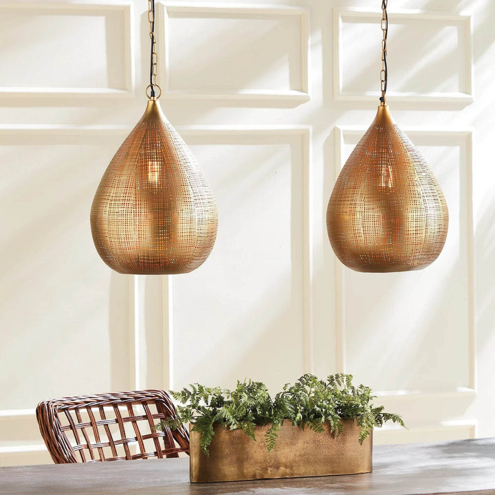 Pair of small gold woven iron pendants above a dining table with greenery, woven chairs and paneled walls, Transitional style