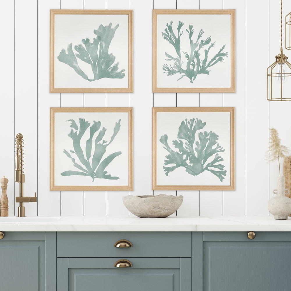 Set of four soft green coral silhouette prints displayed above a console in a bright living room with fabric-wrapped frames – Coastal