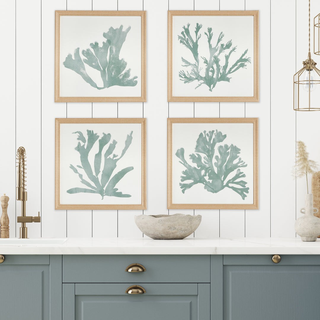 Set of four soft green coral silhouette prints displayed above a console in a bright living room with fabric-wrapped frames – Coastal