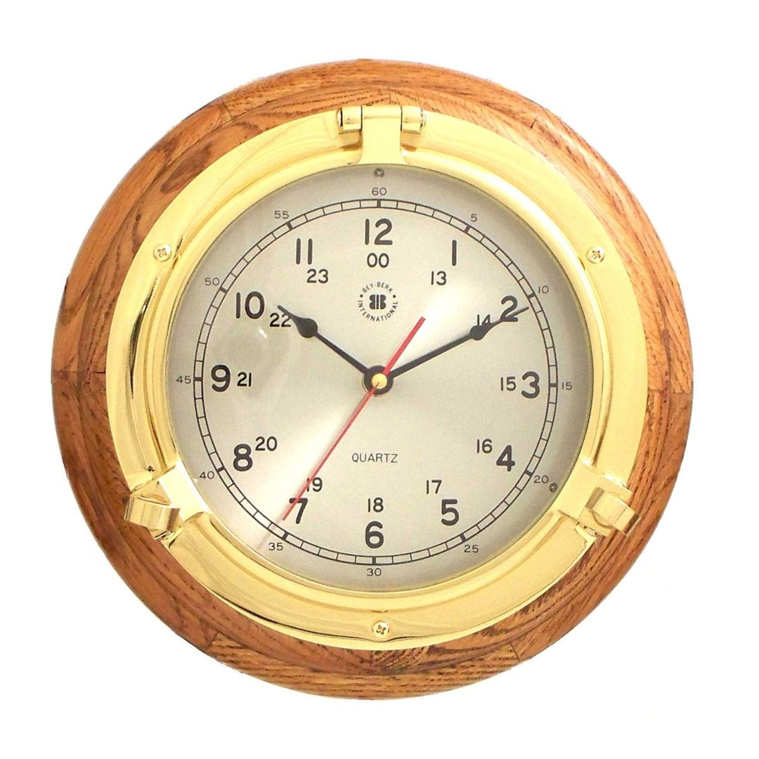 Solid brass porthole wall clock with oak wood frame and round quartz dial shown front view for coastal office Coastal Heritage style