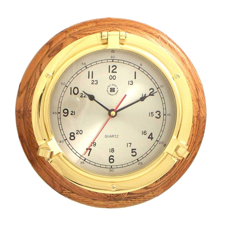 Solid brass porthole wall clock with oak wood frame and round quartz dial shown front view for coastal office Coastal Heritage style