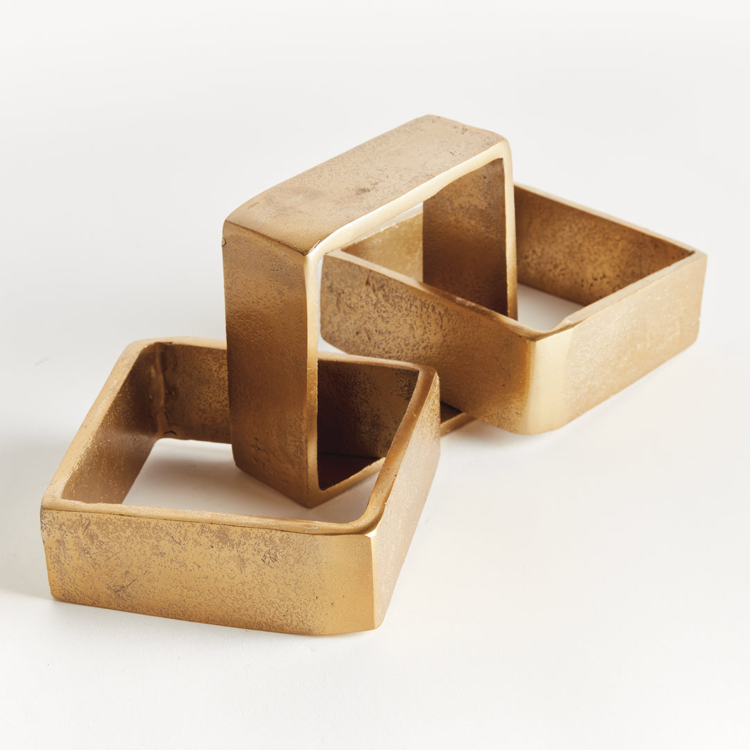 Angled view of gold chain-link sculpture with three cast aluminum links, open centers and textured metal - Modern Organic