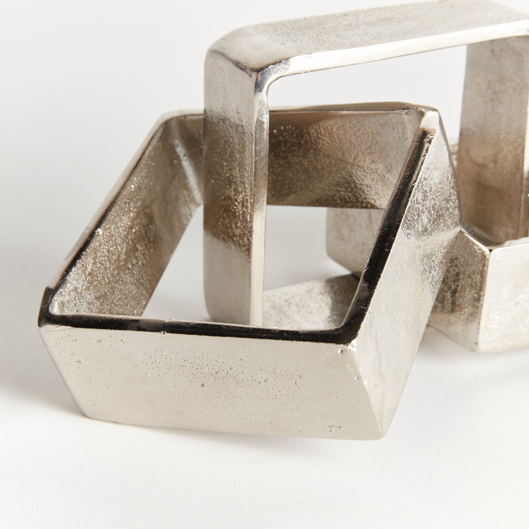 Close view of silver chain-link sculpture showing overlapping square links, textured aluminum and wide bands - Modern Organic