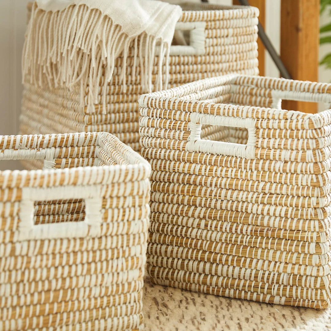Square woven storage baskets with handles shown grouped together on floor, perfect for functional and decorative storage.

