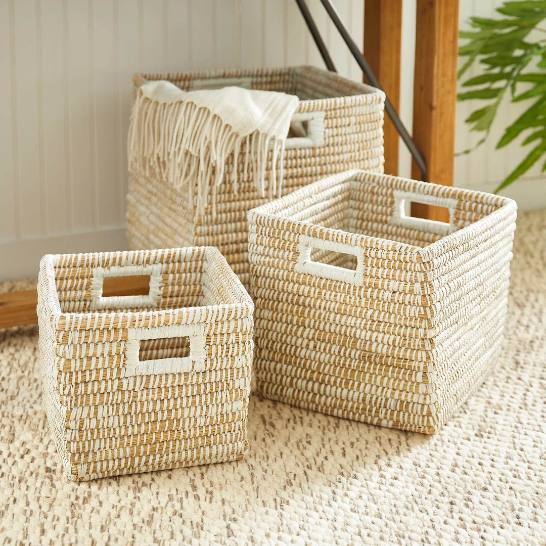 Set of three square woven storage baskets with handles, displayed on neutral rug, ideal for home organization and decor.

