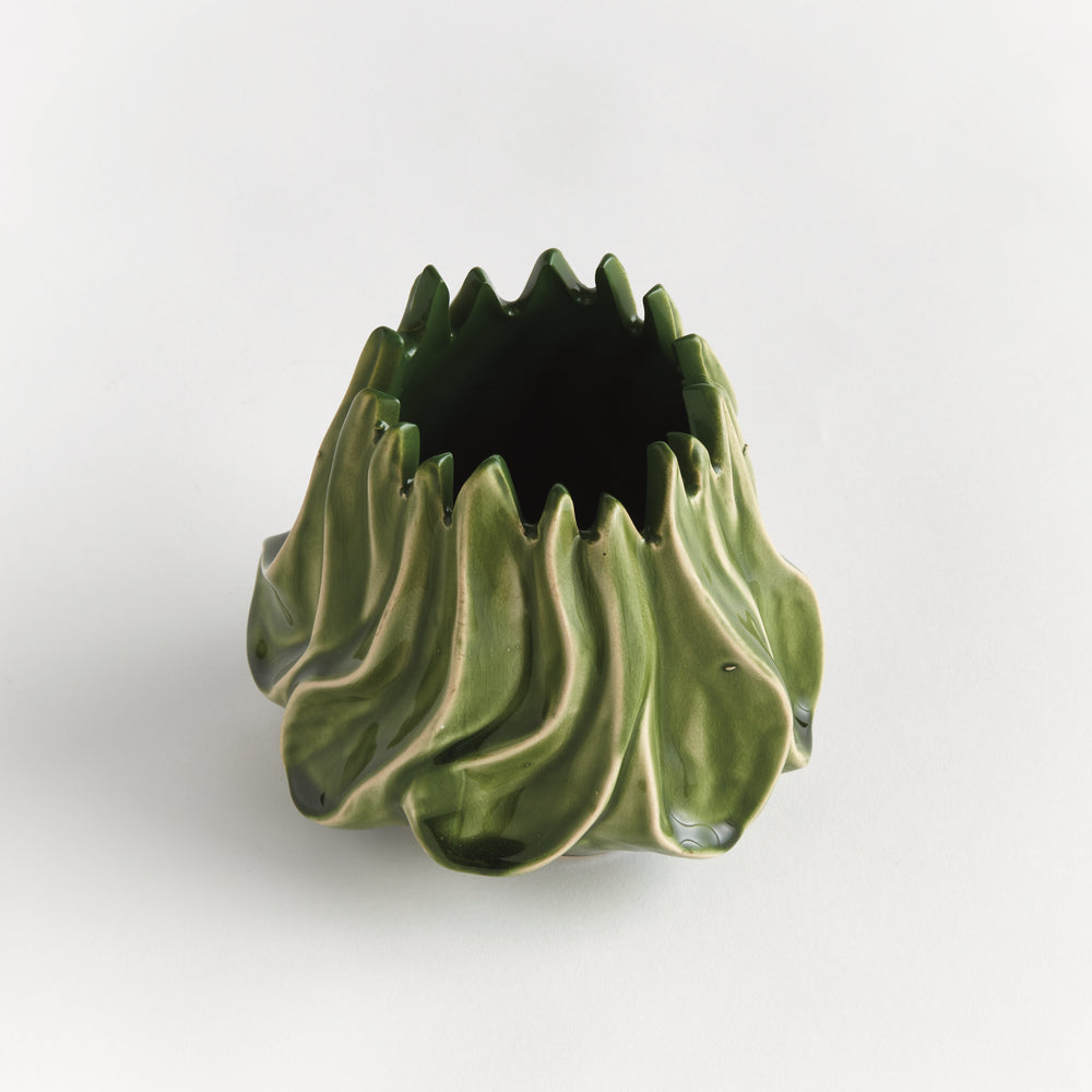 Angled view of Sylva small green vase showing its pointed rim and curved glazed body on a pale background. Modern Organic
