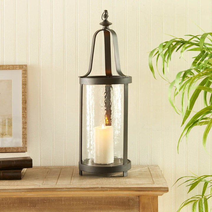 Tall black lantern with hammered glass shown on entryway table, styled with greenery for warm farmhouse or transitional decor.

