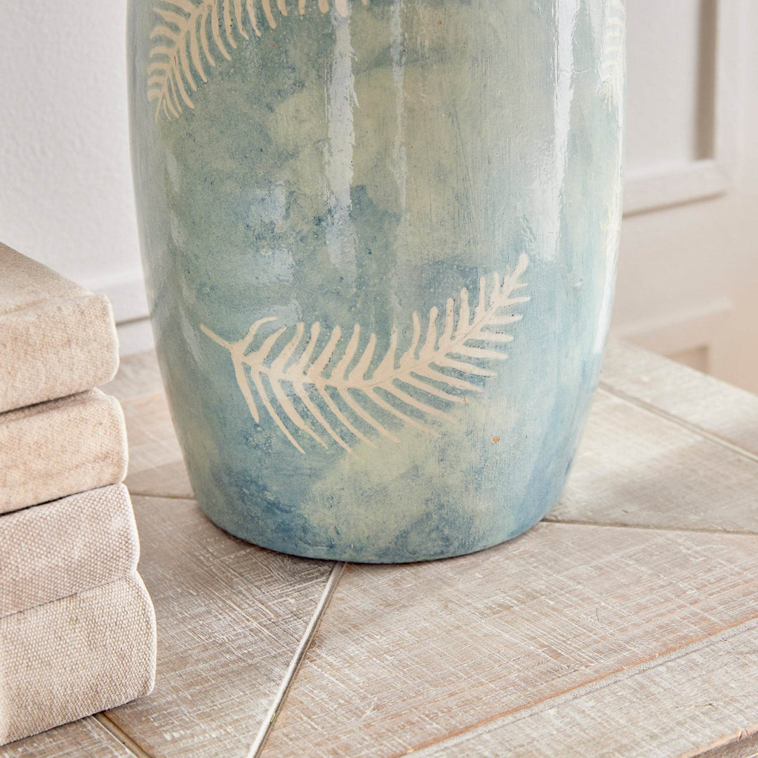 Blue decorative vase styled on a wood console with neutral accents and soft lighting