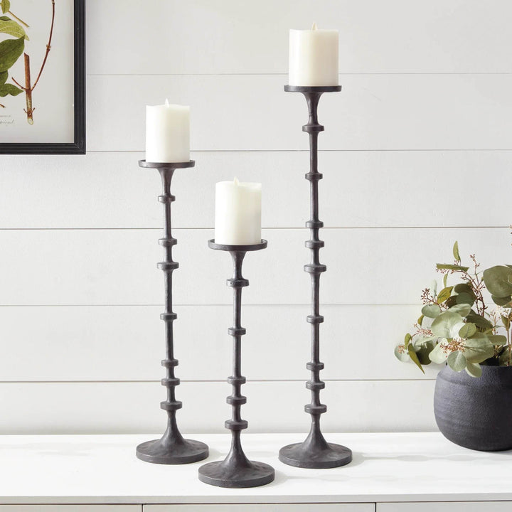 3 tall industrial black bronze candle holders styled with black vase and greenery on white surface – Contemporary
