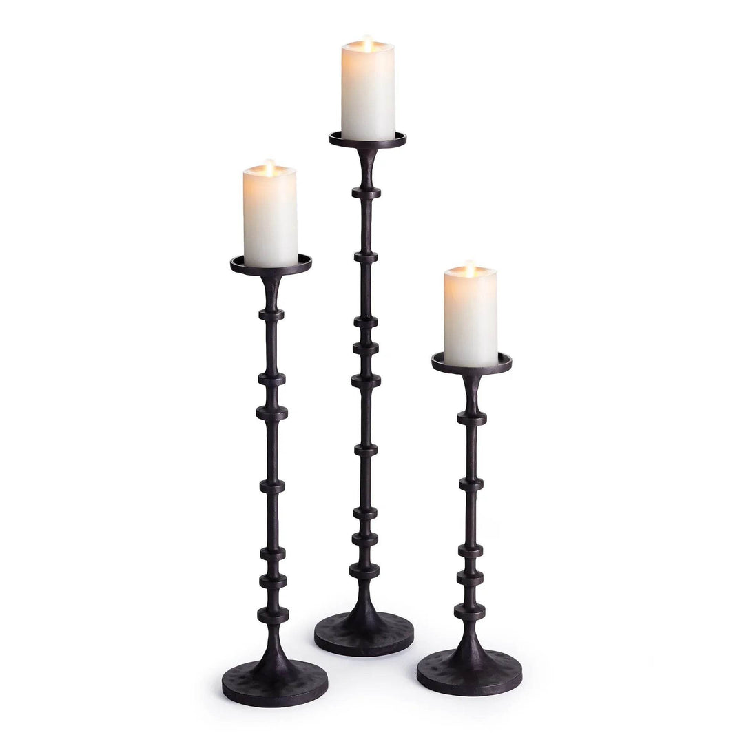 Trio of tall industrial black bronze candle holders shown with white pillar candles in graduated heights – Transitional Decor