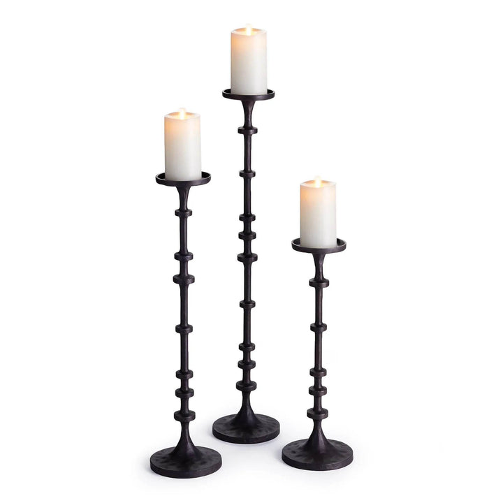 Trio of tall industrial black bronze candle holders shown with white pillar candles in graduated heights – Transitional Decor