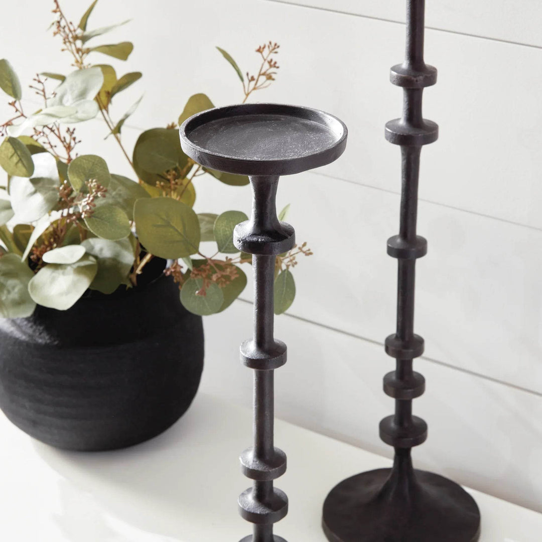Single tall industrial black bronze candle stand with notched column styled with greenery and black vase – Minimal Modern