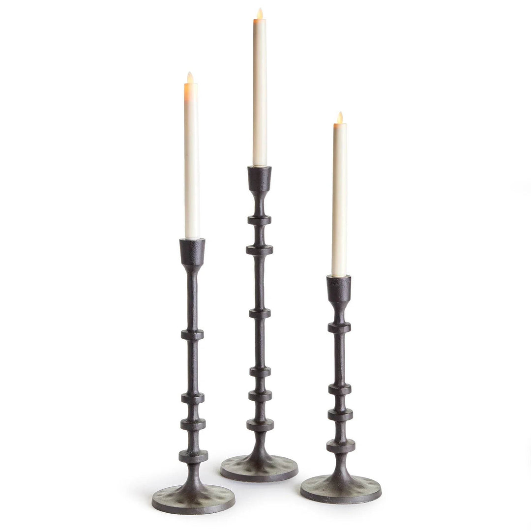 Set of three bronze industrial taper candle holders in graduated heights with candles