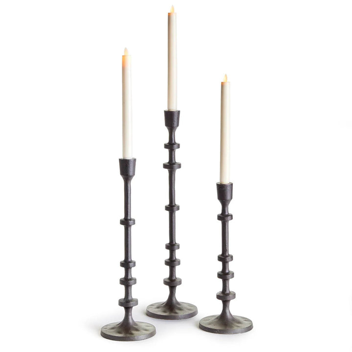 Set of three bronze industrial taper candle holders in graduated heights with candles