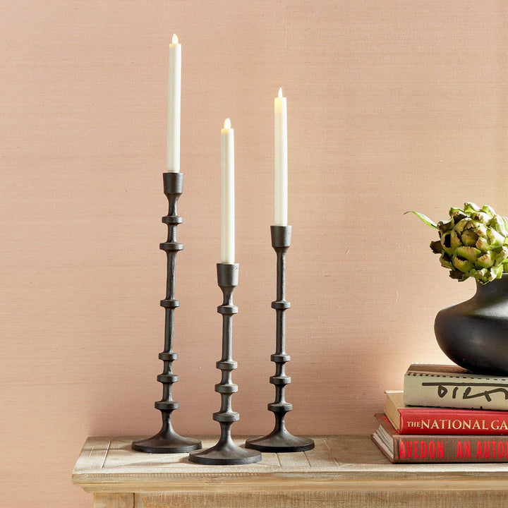 Tall industrial bronze taper candle holders set of 3 styled on books with taper candles