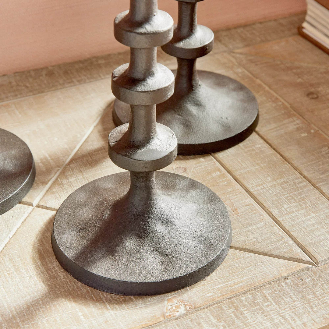Side view of tall bronze taper candle holders set of three on wooden tabletop