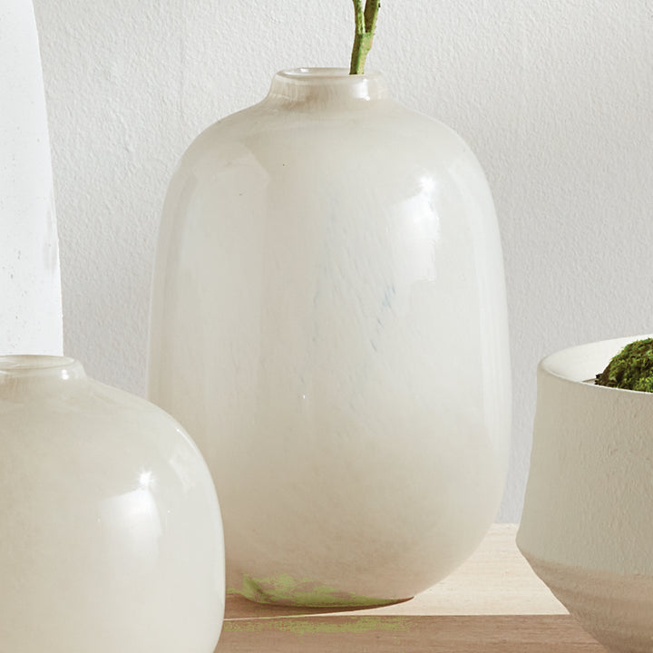 Tall Ivory glass vase beside its lower rounded companion on a pale console, with stems rising above, Modern Organic style