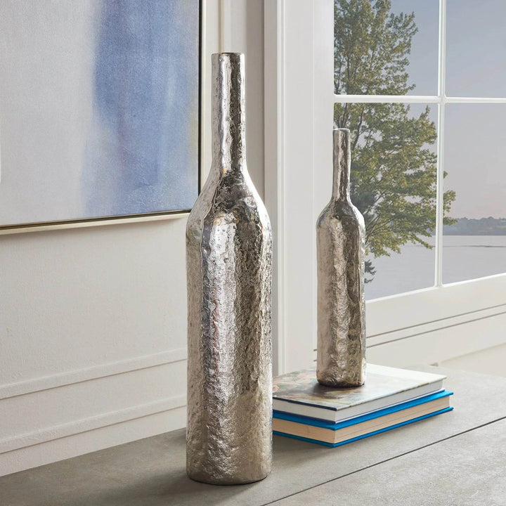 Tall silver hammered aluminum vase styled on console table near window in modern classic setting.

