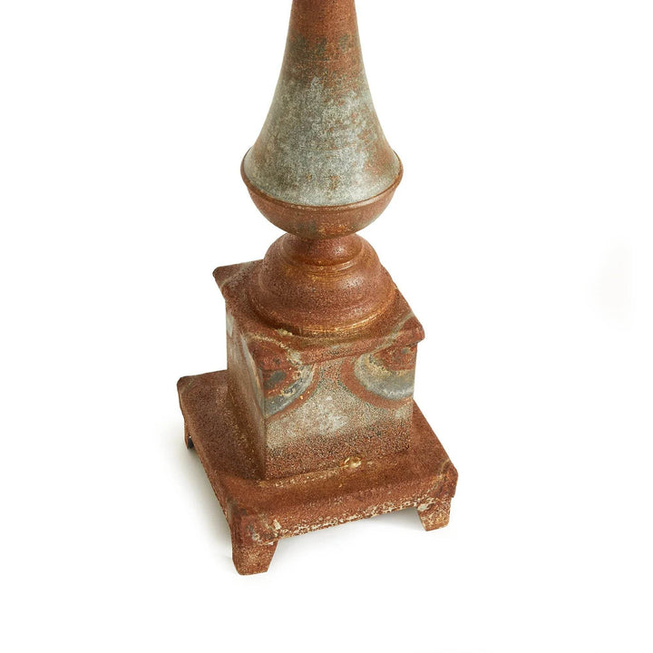 Angled view of tall weathered metal decorative finial with antique galvanized finish on woven rug, iron decor accent for home – Vintage Farmhouse.

