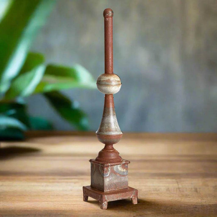 Tall weathered metal decorative finial on wood surface with greenery background, antique galvanized iron accent for home styling – Vintage Farmhouse.

