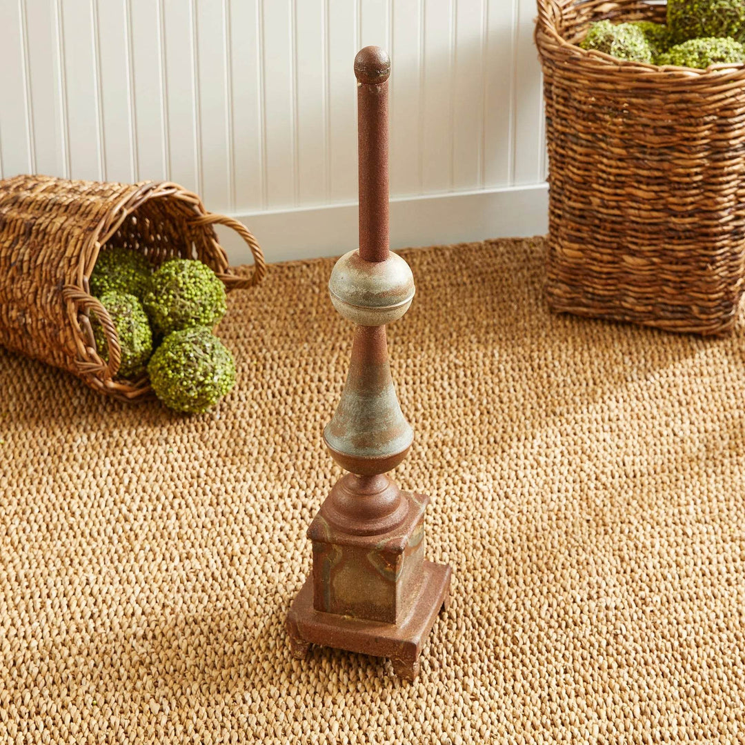 Tall weathered metal decorative finial styled with woven baskets on textured rug, antique galvanized finish home accent – Vintage Farmhouse.

