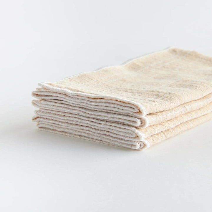 Stacked taupe cotton napkins show soft texture and stitched edges in a set of four reusable dinner linens - Modern Organic.