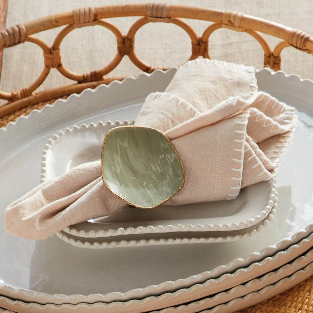 Taupe cotton napkin styled on a plate with napkin ring, layered place setting with rattan charger – Modern Farmhouse.