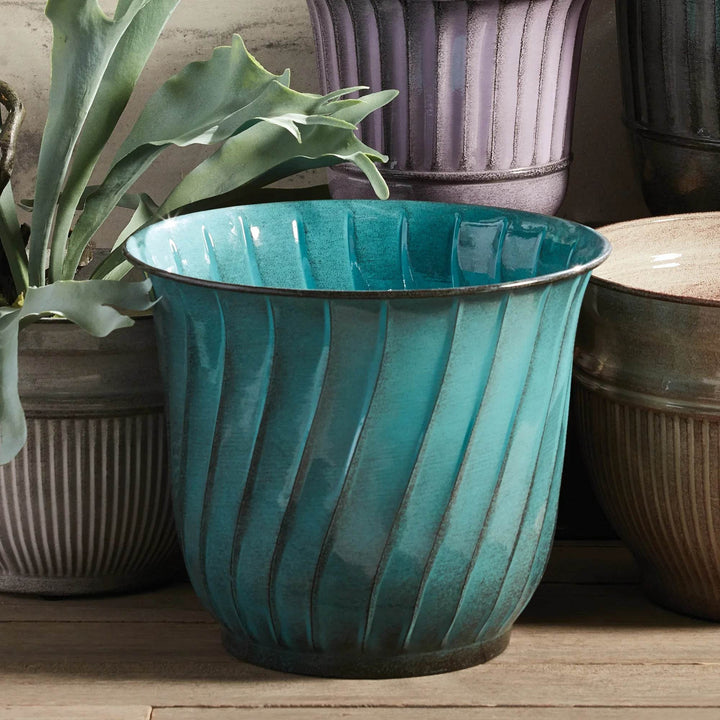 Close-up of teal fluted planter styled with succulents, showcasing the glossy enamel finish in a light-filled indoor garden space.