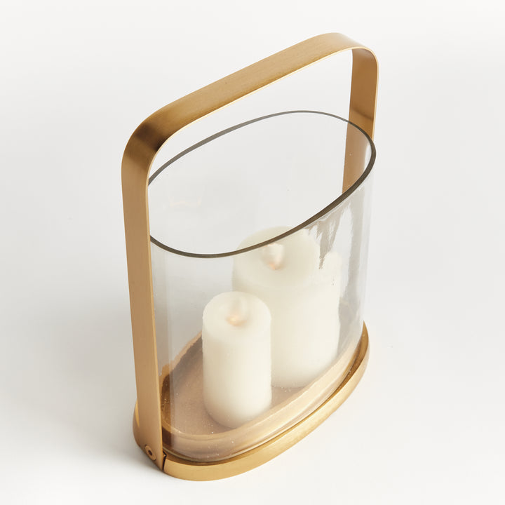Side angle of the small transitional brass and glass hurricane candle holder with cylindrical glass and brass frame.