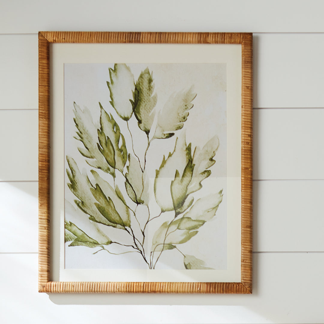 Green coastal botanical print displayed on a wall, with ivory matting and a natural rattan-wrapped rectangular frame. Coastal