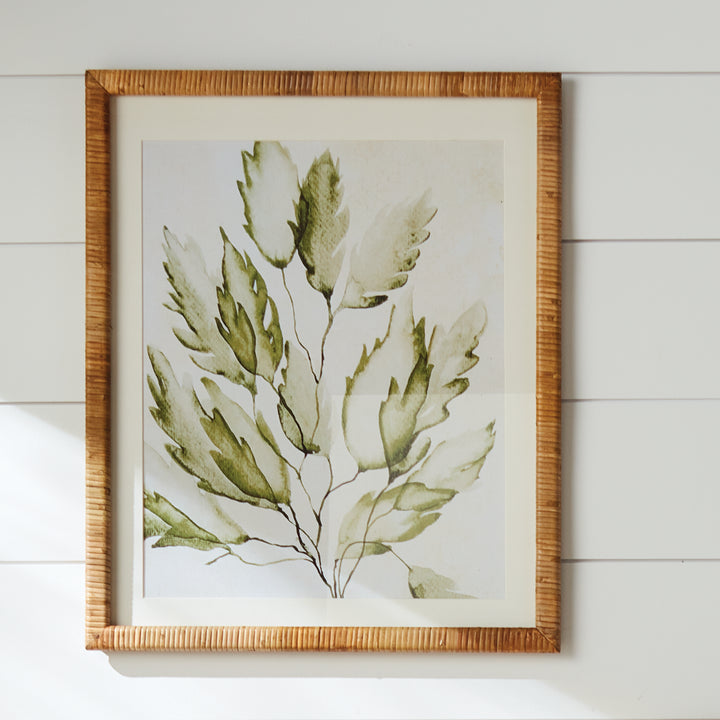 Green coastal botanical print displayed on a wall, with ivory matting and a natural rattan-wrapped rectangular frame. Coastal