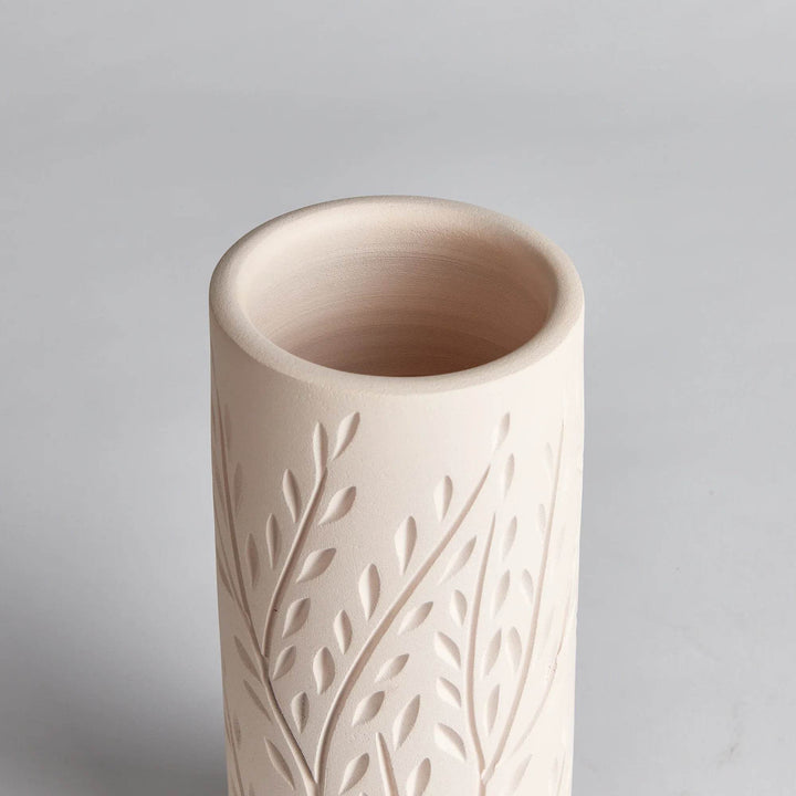 Detail of vine motif carving on handcrafted beige terracotta vase, showcasing texture and artisan craftsmanship.


