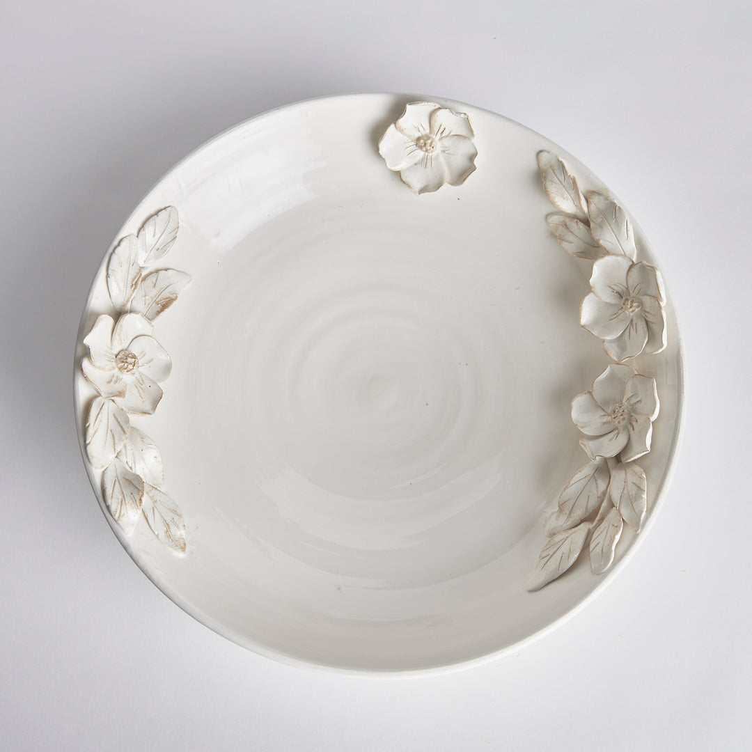 Overhead view of a white ceramic decorative bowl showing its broad interior and raised floral rim detail in Traditional style