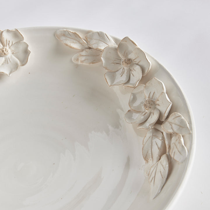 Detail of sculpted dogwood petals and leaves around the rim of a softly glazed white ceramic bowl, shown in Traditional style