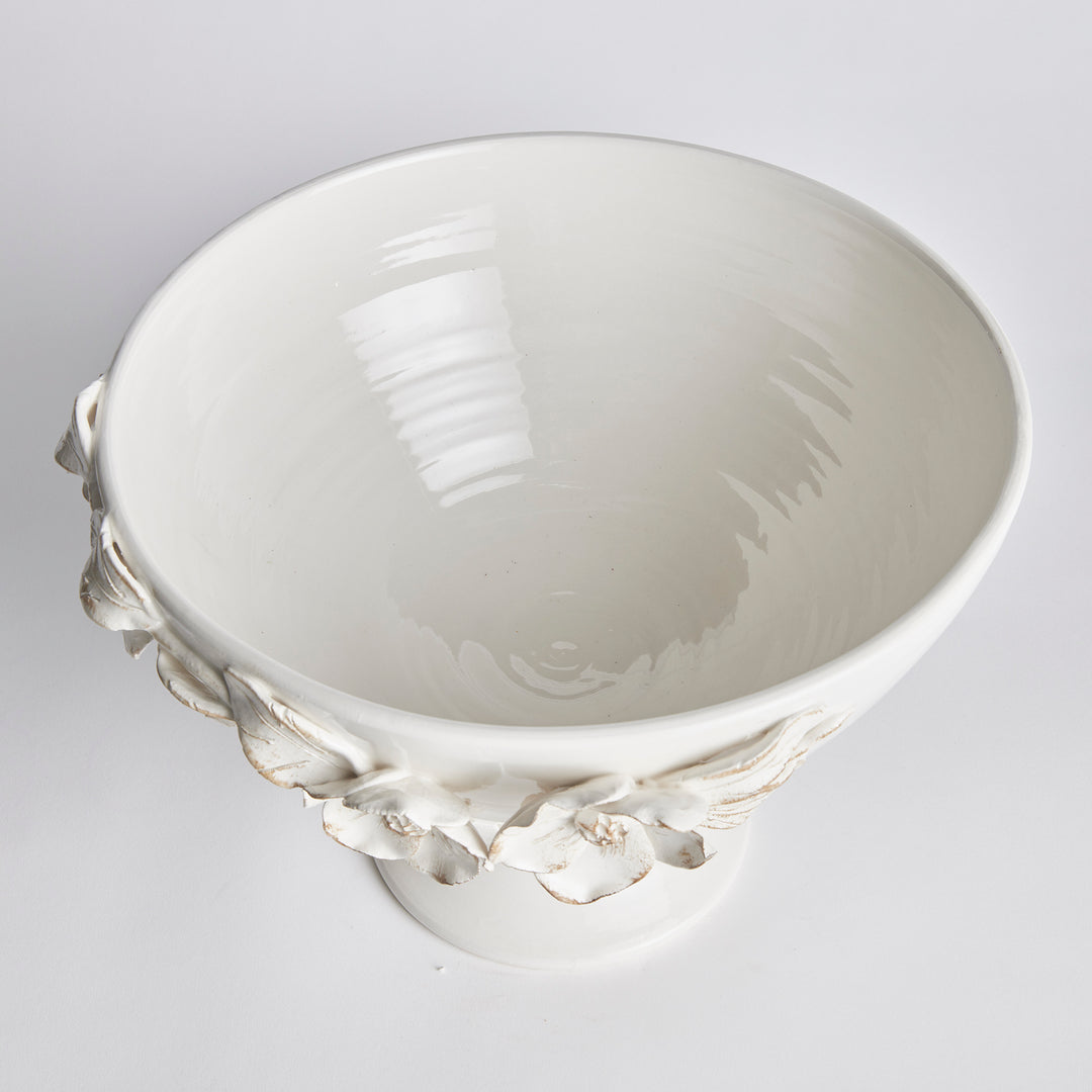 Overhead view of a white ceramic footed bowl showing a glazed interior and raised flowers around the rim in Traditional style