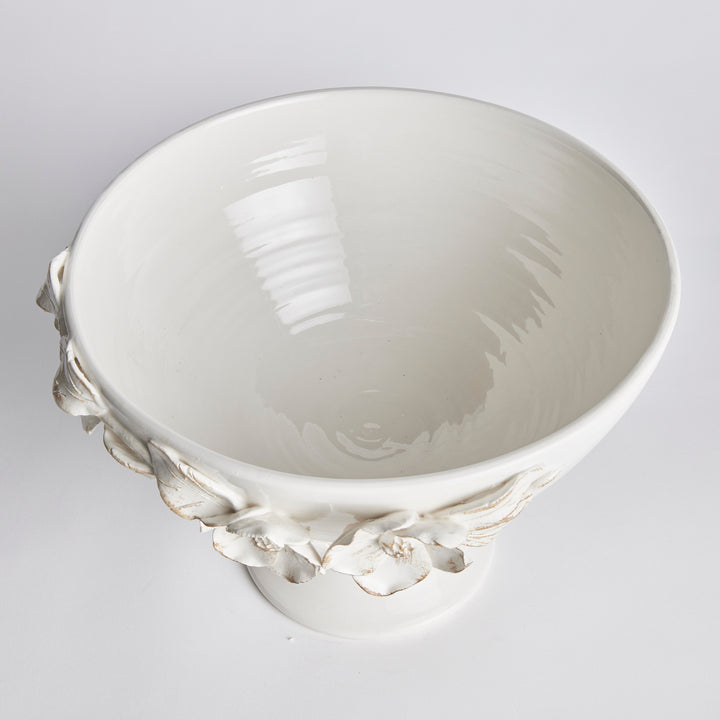 Overhead view of a white ceramic footed bowl showing a glazed interior and raised flowers around the rim in Traditional style