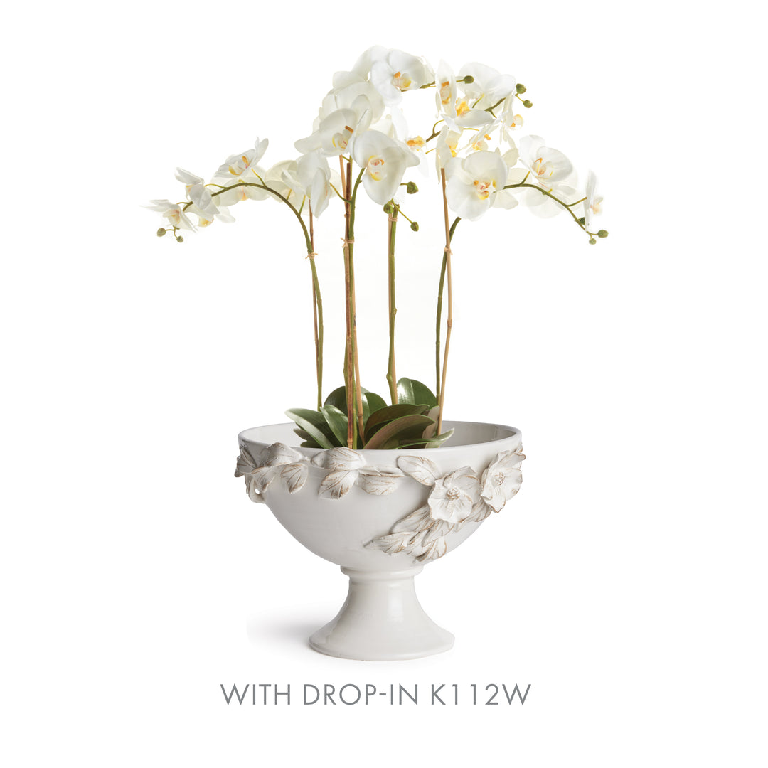 White floral pedestal bowl styled with a cream artificial orchid drop-in and green leaves at the base in Traditional style